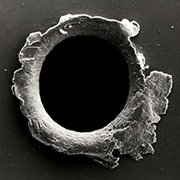 View of an orbital debris hole made in the panel of the Solar Max experiment. Credit: NASA.